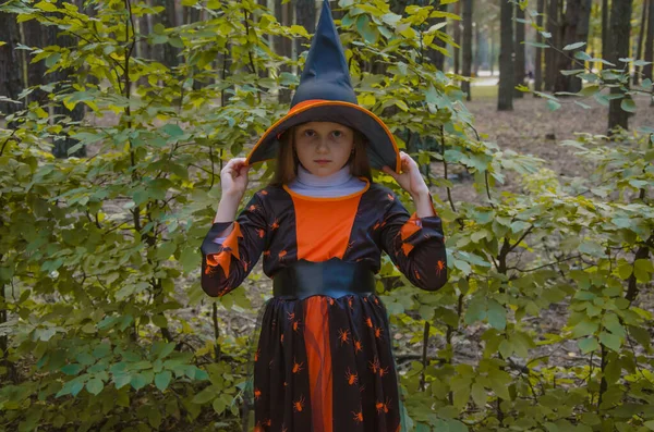 Cute Girl Witch Costume Puts Witch Hat Her Head Holiday — Fotografia de Stock