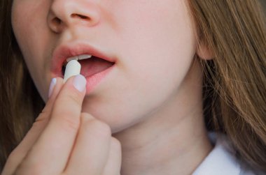 Kız ağzına beyaz hap koyuyor. tıp konsepti