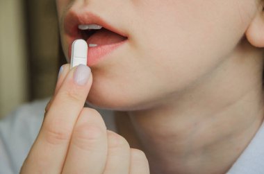 Kız ağzına beyaz hap koyuyor. tıp konsepti