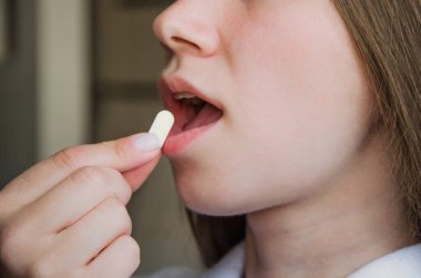 Kız ağzına beyaz hap koyuyor. tıp konsepti