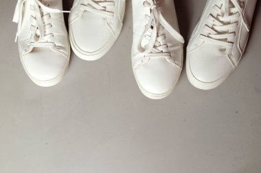 Klasik beyaz spor ayakkabılarının yatay fotoğrafı. Fotoğrafın tepesinde ve altta çimentoda boşluk bırakıyor.