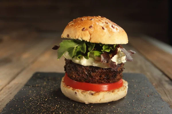 Köy masalarında kalın etli, peynirli ve sebzeli hamburger.