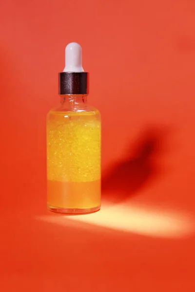 オレンジ色の背景と光と影に美容液とガラスのアイドロッパーとフランク — ストック写真