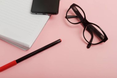 Pembe arka planda gözlüklü, cep telefonlu ve kalemli gündem