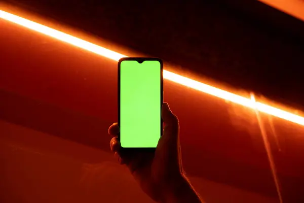 Gece sokakta elinde cep telefonu olan bir adam. Sokakta kırmızı ışık yakıyor.