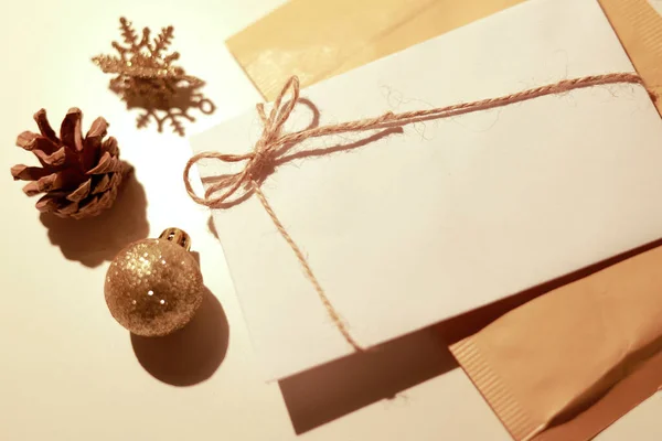Etrafında altın Noel süsleri olan beyaz bir zarf.