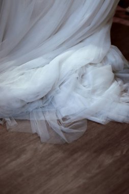 Beyaz gelinlik kumaşı ahşap bir zeminde toplandı ve hassas bir doku oluşturdu.
