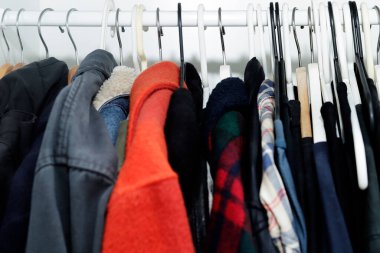 Farklı askılarla asılmış sıradan erkek kıyafetleri.