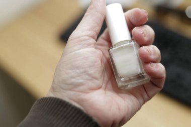 Beyaz el beyaz tırnak cilası kabı tutuyor.