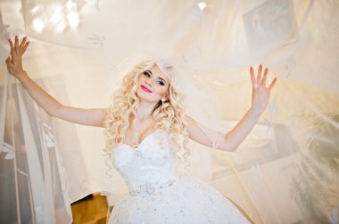 Perdeler üzerinde poz kıvırcık sarışın gelin