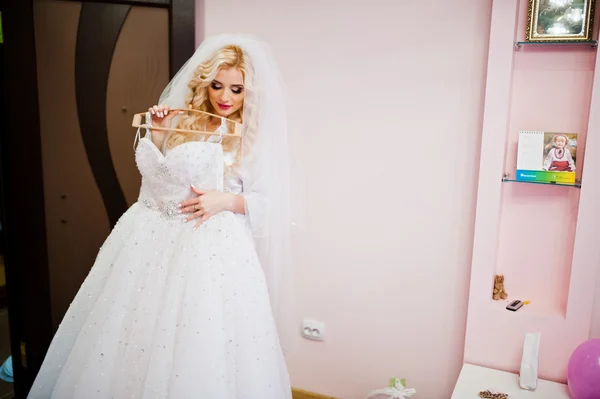 Junge schöne blonde Braut schaut auf ihr Hochzeitskleid — Stockfoto