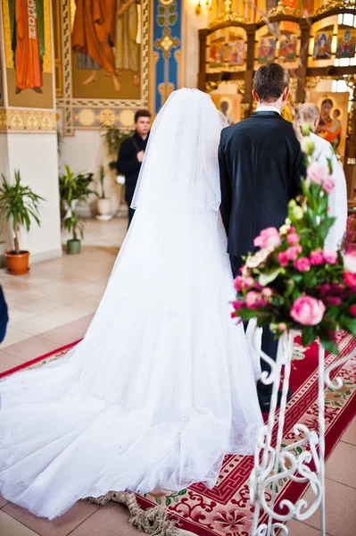 Achterkant van elegante bruidspaar bij de kerk — Stockfoto