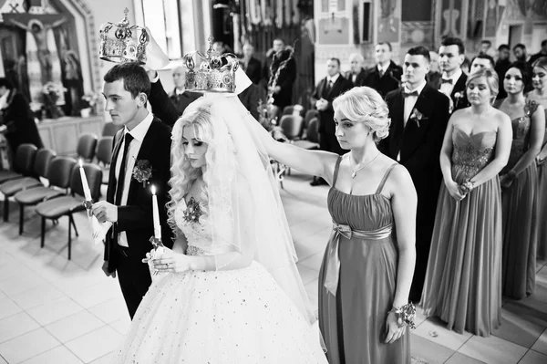 Bridesmaid holding crown on had of newlyweds at churh — Stock Photo, Image