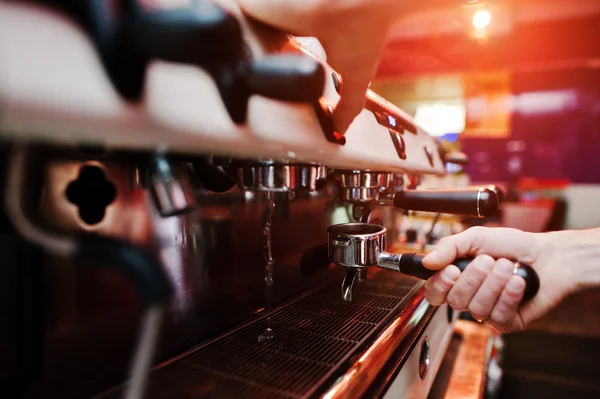 Professional barman at coffee machine with vapor making espresso