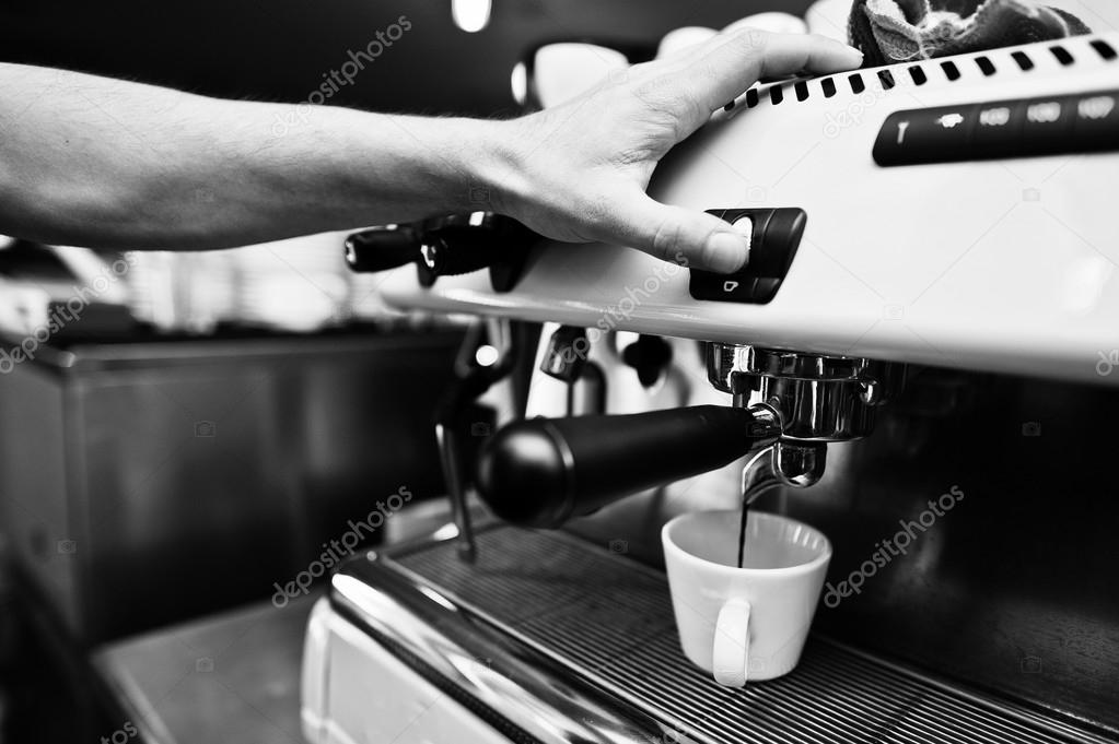 Professional barman at coffee machine making espresso in a cafe