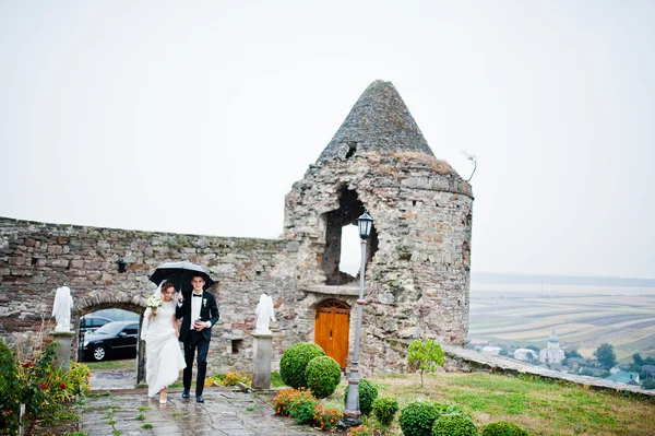 Свадебная пара, идущая под дождем с зонтичной башней — стоковое фото