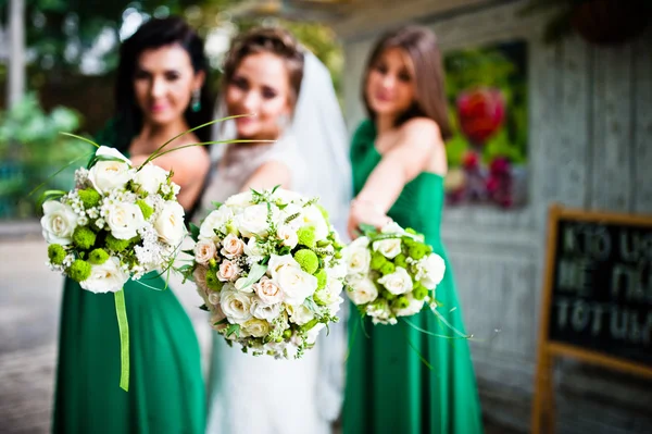 Thre charmante Braut und Brautjungfern zeigen Hochzeitssträuße bei — Stockfoto