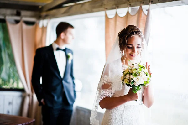 Noiva encantadora olhou para o noivo de fundo do buquê de casamento — Fotografia de Stock