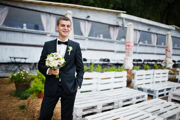 Portret van elegante bruidegom bruiloft boeket bij de hand — Stockfoto