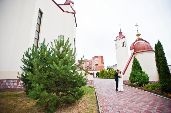 結婚式のカップルが教会の鐘タワーの近くを歩く — ストック写真