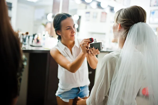 Artista de maquiagem de casamento em shorts jeans sexy curtos aplicando perfu — Fotografia de Stock