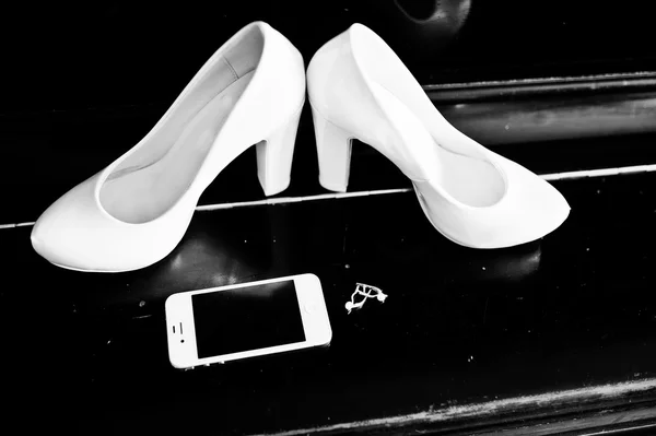Белые свадебные туфли невесты в фортепиано с телефоном и серьгами — стоковое фото