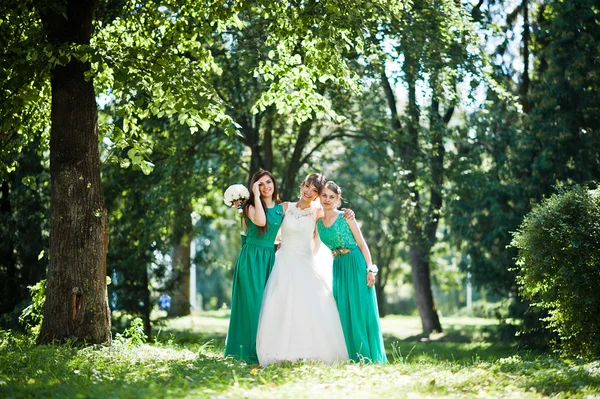 Hermosa novia con damas de honor posadas en el parque del sol —  Fotos de Stock