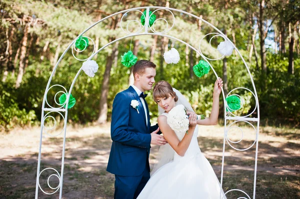 Mooie bruidspaar op zonnige dag op grenen hout in de buurt van decor weddi — Stockfoto