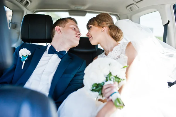 Wedding couple in the back seat of car — Stock Photo, Image