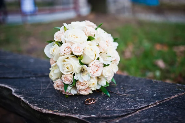 Ramo de boda de rosas con anillos en banco de madera — Foto de Stock