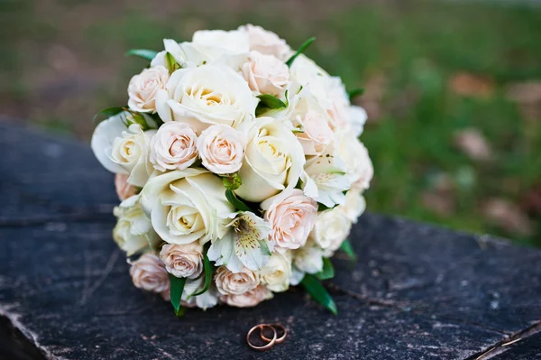 Ramo de boda de rosas con anillos en banco de madera — Foto de Stock