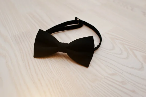 Gravata de arco de algodão preto no fundo de madeira leve — Fotografia de Stock