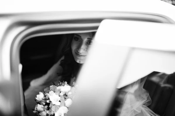 Jolie mariée bouclée à la recherche de voiture de mariage élégante — Photo