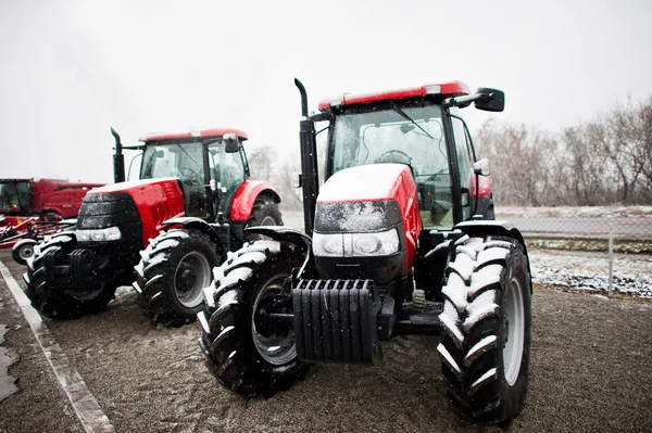 Twee nieuwe rode trekker verblijf in het besneeuwde weer achtergrond combineren — Stockfoto