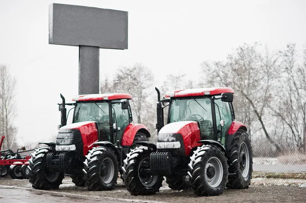 Dos nuevos tractores rojos permanecen en el clima nevado — Foto de Stock