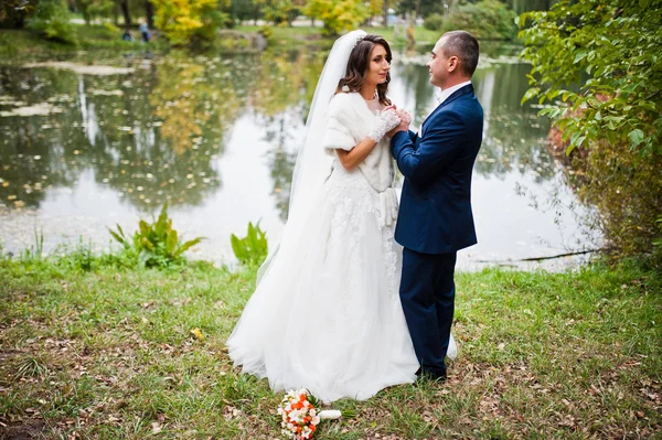 Esküvői pár háttérben kövek és őszi tó — Stock Fotó