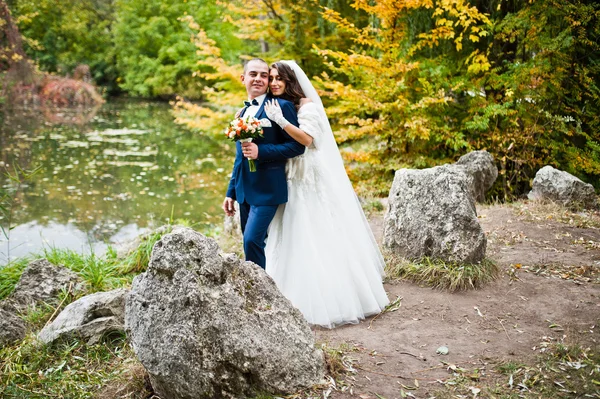 Свадебная пара фоновые камни и озеро осенью — стоковое фото
