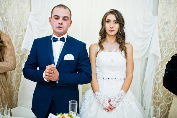 Couple de mariage à la table du restaurant, les mains pliées pour prier — Photo