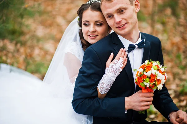 Happy wedding couple sitting at autumn forest with fell leaves f — Stock Photo, Image