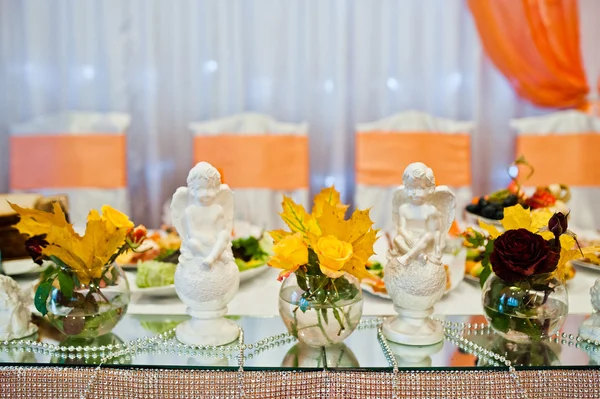 Hojas amarillas de otoño en jarrones con ángeles de yeso en la boda —  Fotos de Stock