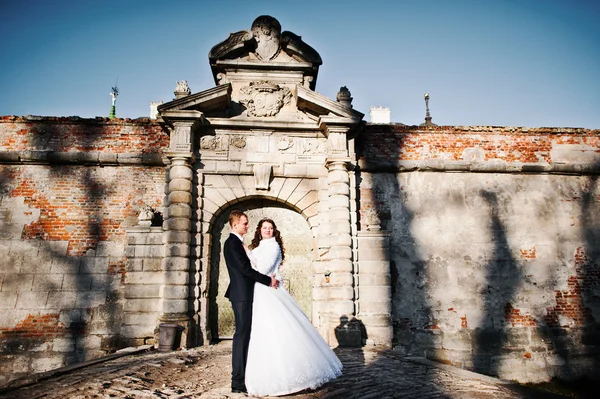 Свадебная пара на солнечном фоне стены со старыми тенями — стоковое фото