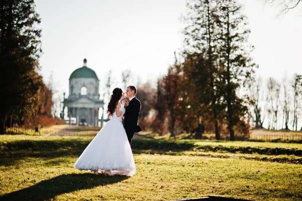 Casal de casamento na moda no fundo do dia ensolarado igreja velha — Fotografia de Stock