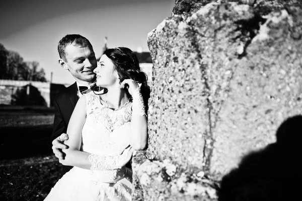 Hochzeitspaar bei Sonnenschein bleibt in der Nähe des alten Denkmals — Stockfoto