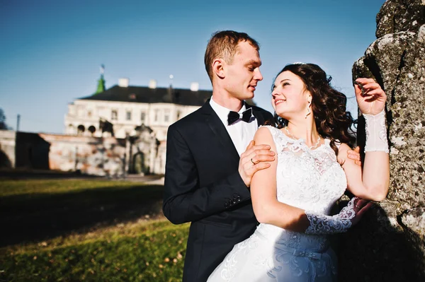 Hochzeitspaar bei Sonnenschein bleibt in der Nähe des alten Denkmals — Stockfoto