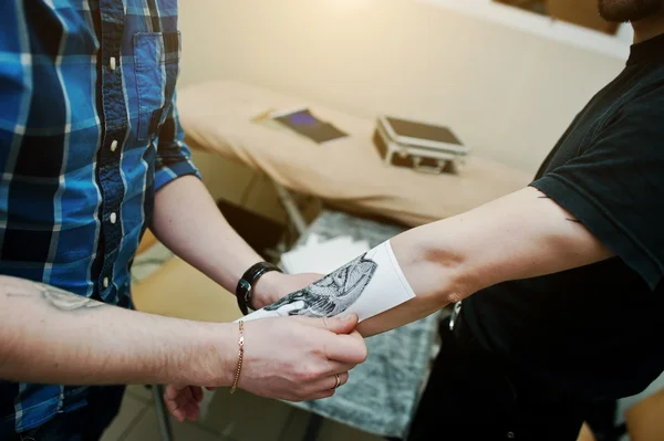 Tattoo master puts sketch at hand of client — Stock Photo, Image