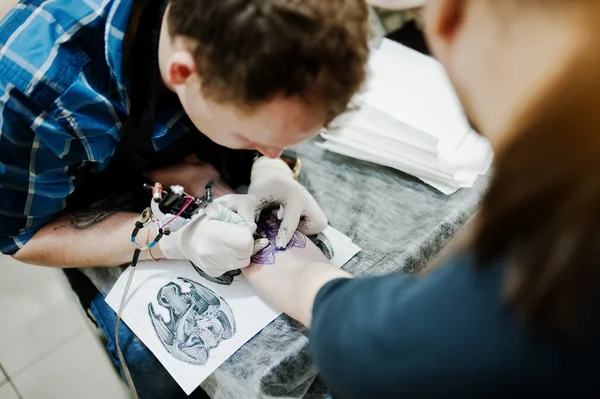 Maestro del tatuaje hacer tatuaje para el hombre rockero en el salón de tatuajes —  Fotos de Stock