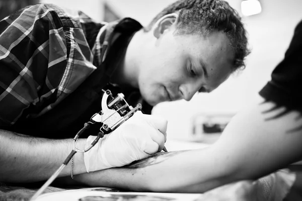 Il maestro del tatuaggio fa il tatuaggio per l'uomo dondolo al salone del tatuaggio — Foto Stock