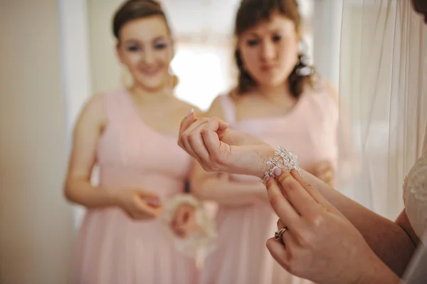 Bride dressed in her room background bridesmaids, wears a bracel — Stock Photo, Image