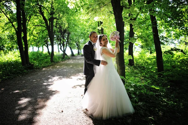 Fashionable wedding couple stay near tree at forest with sun lig — Stock Photo, Image