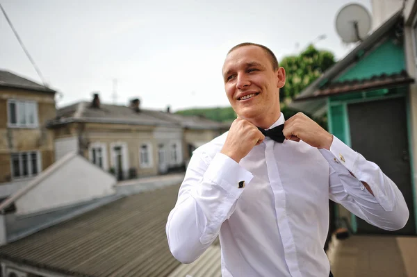 Élégant marié dans une chemise blanche et noeud papillon rester toit arrière . — Photo